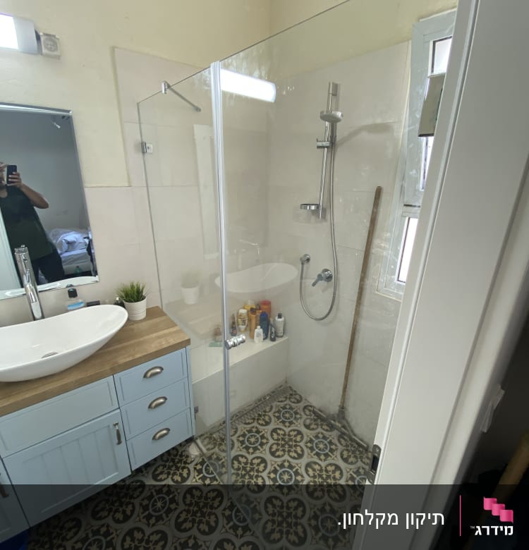 מקלחון זכוכית עם מוצרי טיפוח על המדף